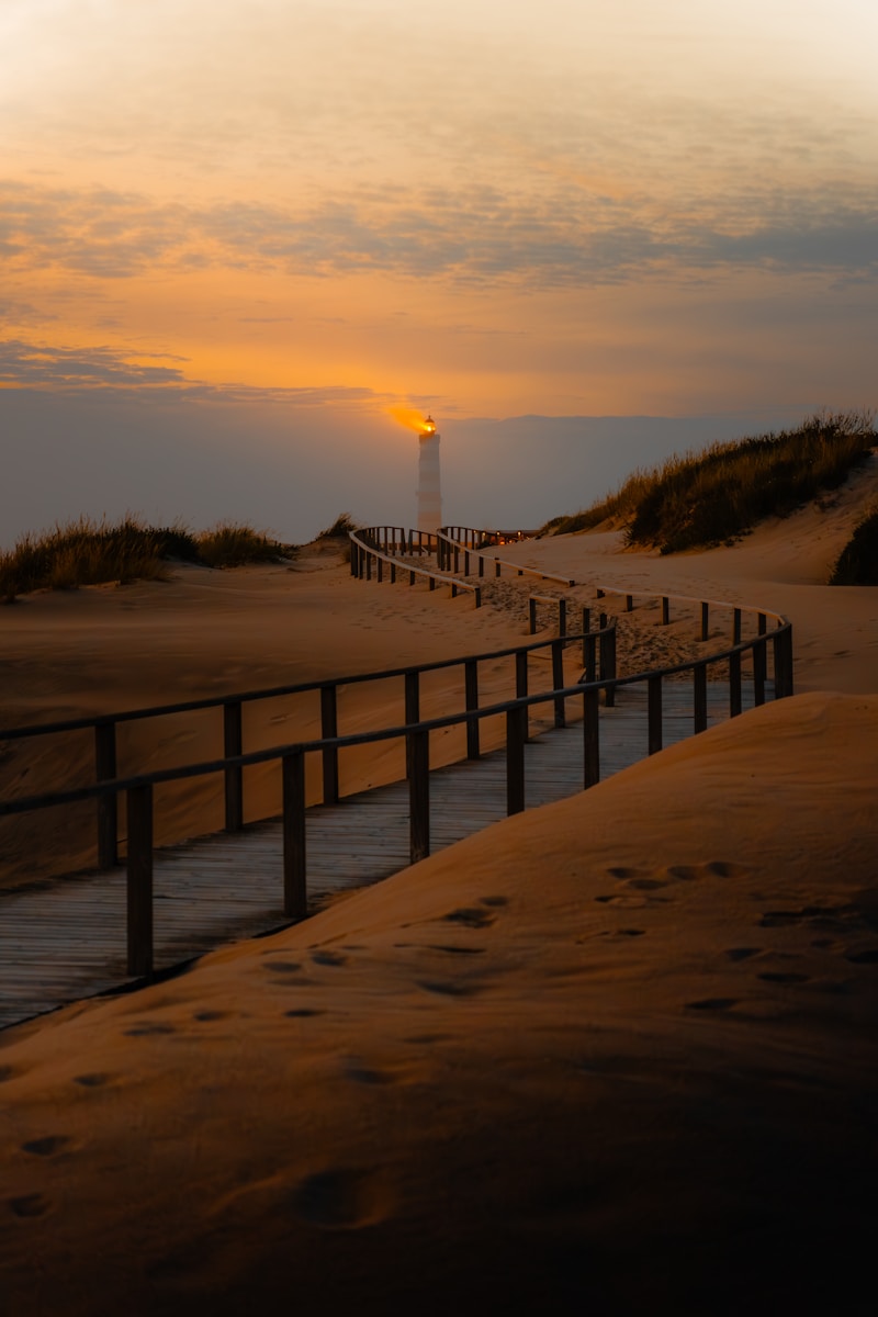 A boardwalk leading to a light house on a beach