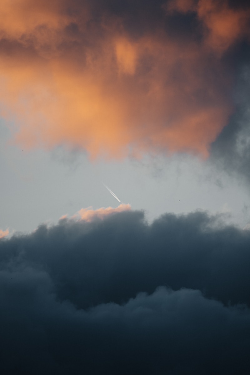 A plane flying through a cloudy sky at sunset